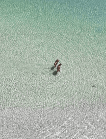 Due persone camminano nell'acqua cristallina.