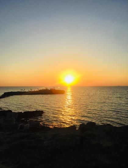 Sonnenuntergang über dem Meer mit goldenen Reflexionen und klarem Himmel.