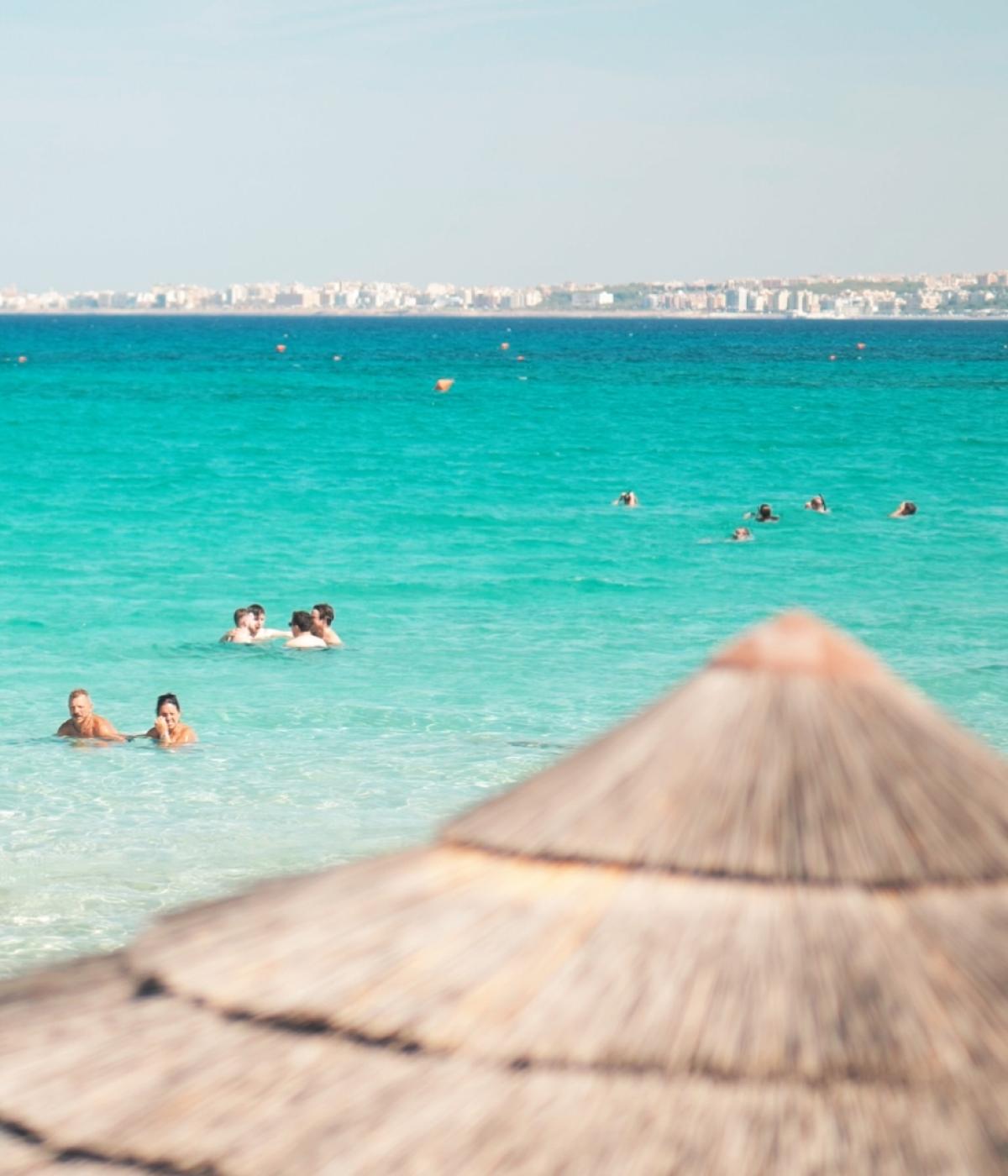 Beach with turquoise water and people swimming.