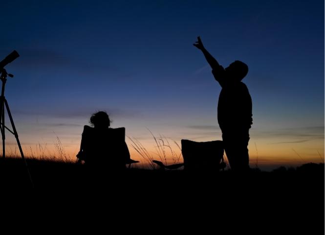 Persone osservano le stelle al tramonto con un telescopio.