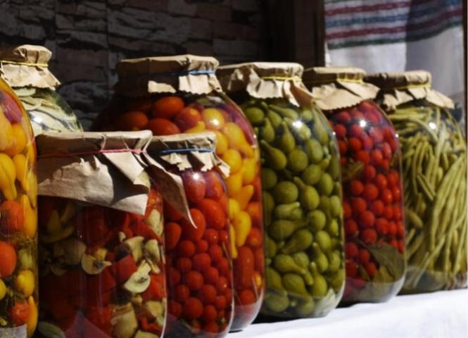 Jars of pickled vegetables on an outdoor table.